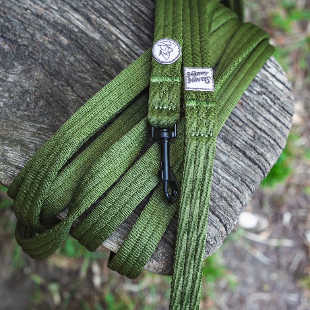 Green paracord on a wooden surface with a blurred natural background