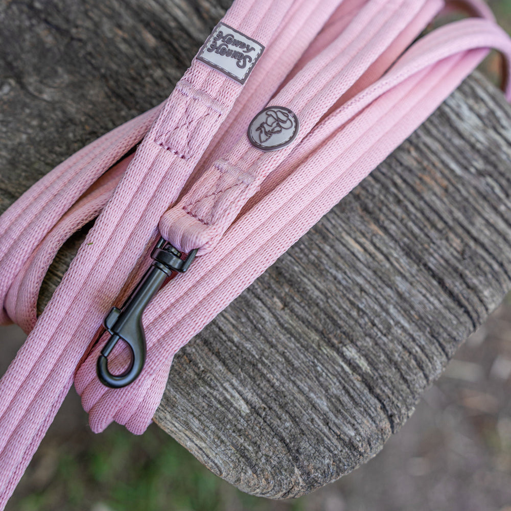 Pink dog leash with a brand label on a wooden surface